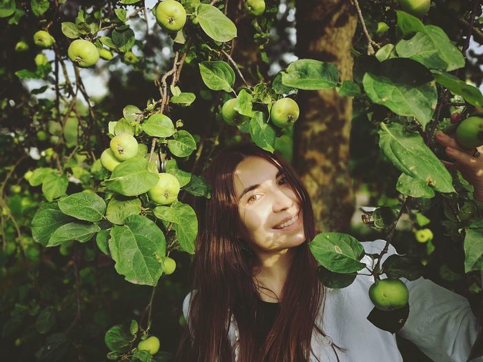 Portrait of smiling woman with fruit tree