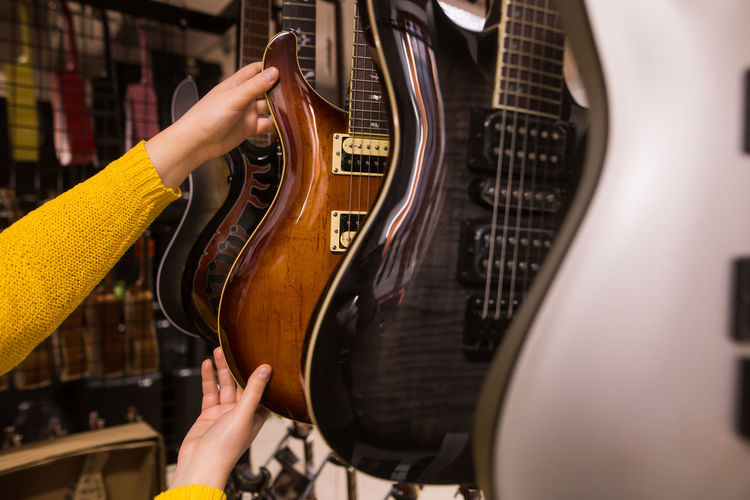 Cropped hand of woman holding guitar at store