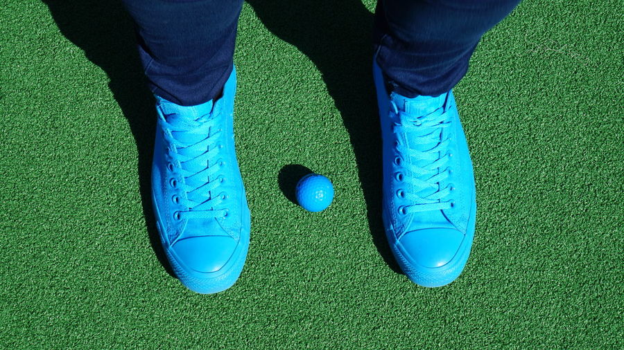 Low section of man standing with blue golf ball