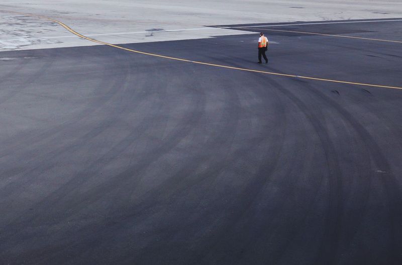 Full length of worker walking on airport runway