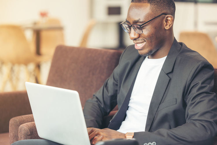 Businessman using laptop while sitting on sofa at home