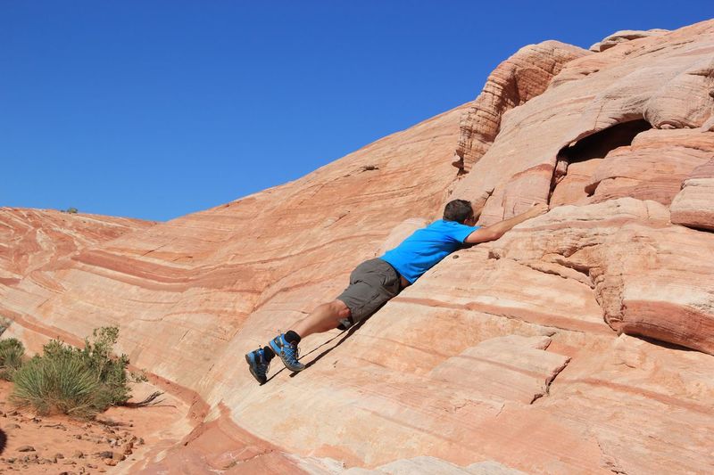 Man clambering on rock without equipment