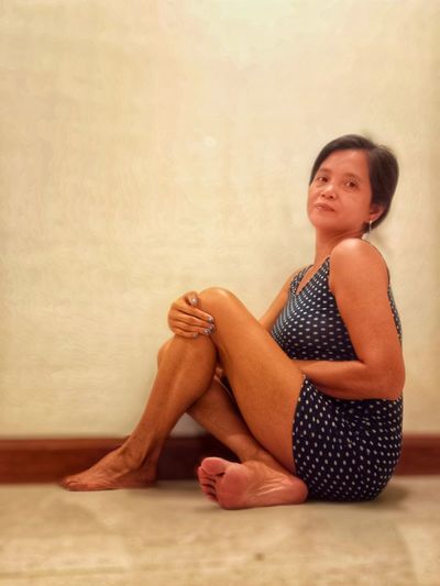 Full length of woman sitting against wall at home