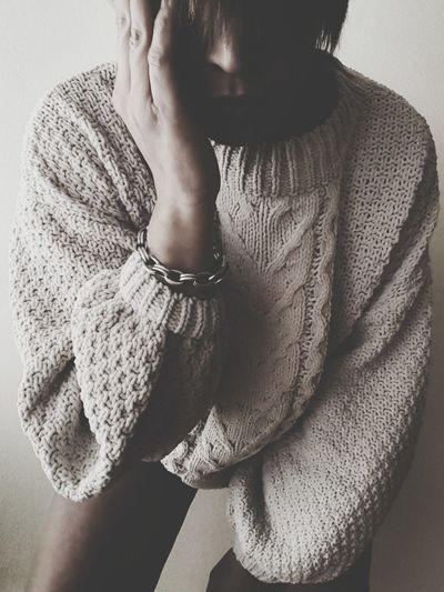 Close-up of mid adult woman in sweater standing against wall