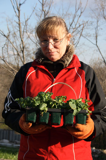 Portrait of woman holding potted plants in seedling tray