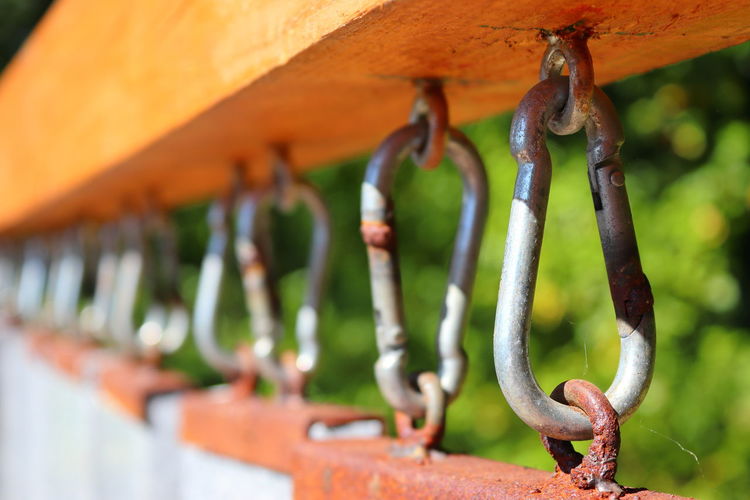 Close-up of rusty chain hanging on metal fence