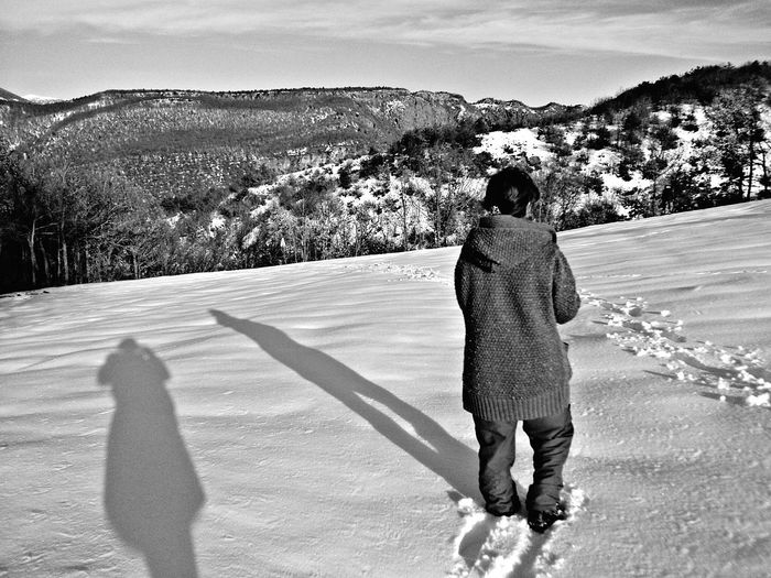 Rear view of person standing on snow covered mountain