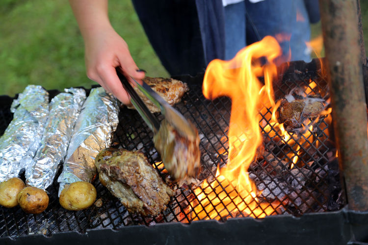 Midsection of man preparing meat on barbecue