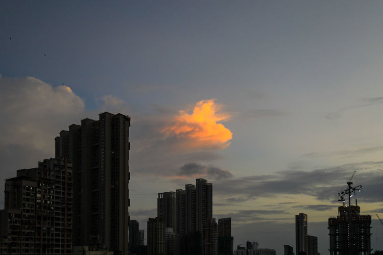 Modern buildings in city against sky during sunset