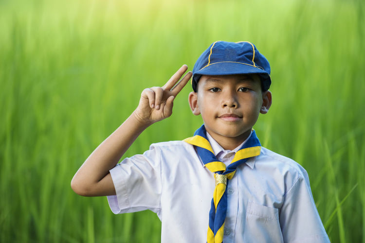 Portrait of boy standing wearing cap gesturing while standing outdoors