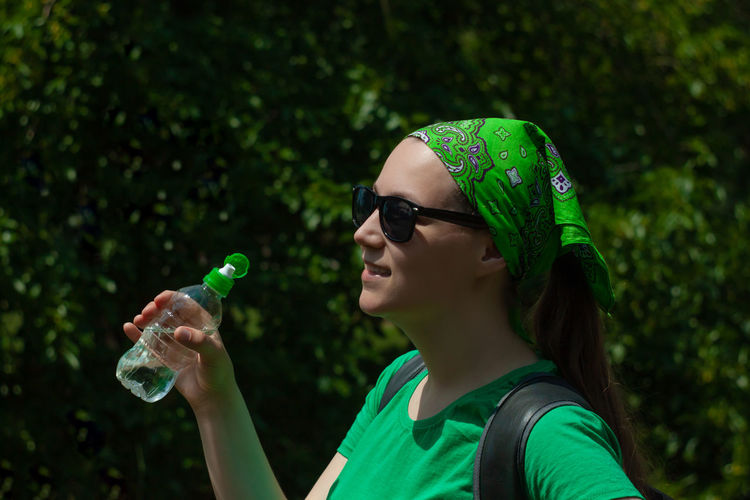 Young girl holds a bottle of water in hand and drinks weight loss, summer active lifestyle body care