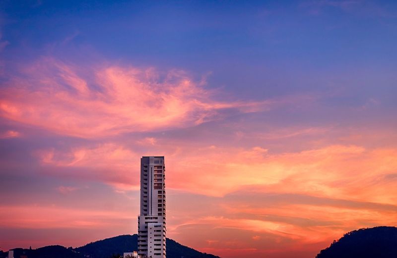 Low angle view of silhouette building against sunset sky