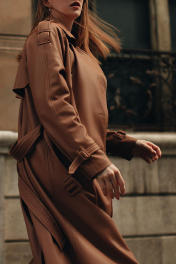 Cropped figure of woman in stylish autumn brown coat. street casual fashion concept