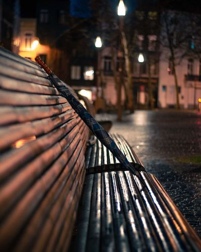 Umbrella on bench against buildings in city at night