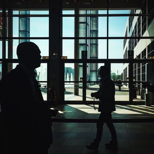 Silhouettes of two men walking in lobby of public building