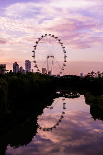 Ferris wheel in city against cloudy sky