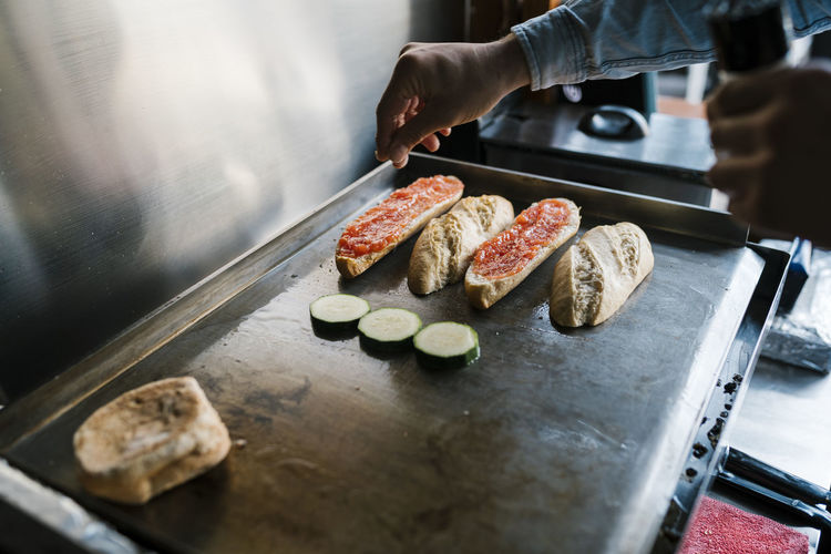 Waiter seasoning veggies while preparing sandwich in a restaurant