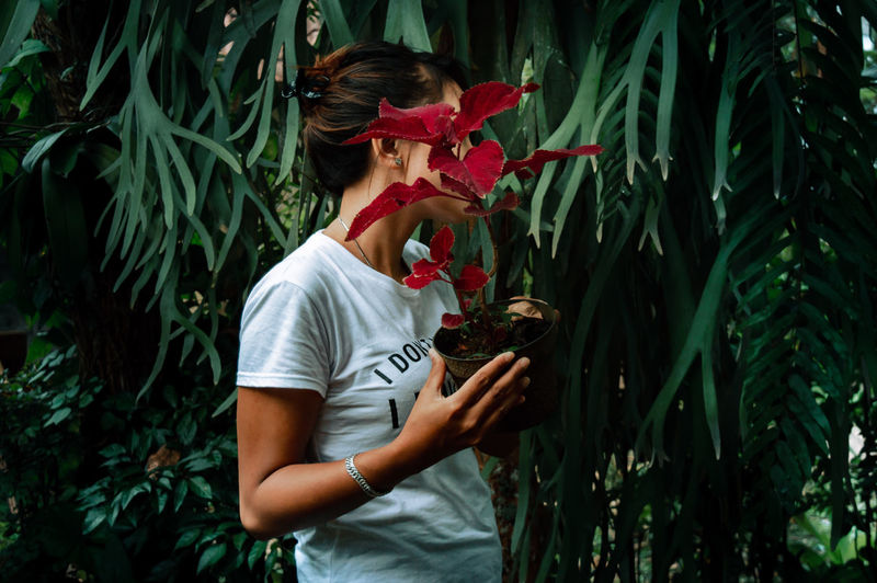 Full length of young woman holding flowering plants