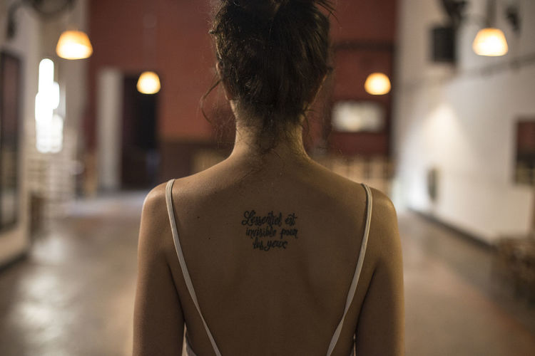 Rear view of woman with tattoo on back at home