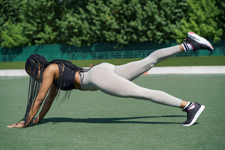 Woman beginner starts intensive training for all types of muscles to keep body fit on sports ground