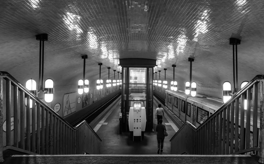 Rear view of man and woman walking at illuminated subway station