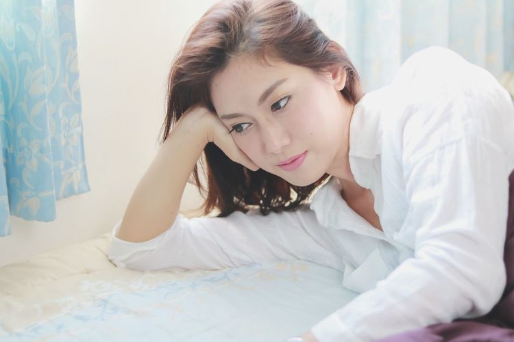 Portrait of young woman lying on bed at home