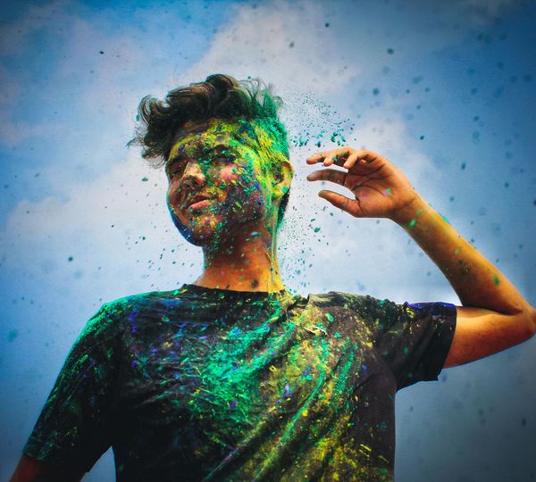 Low angle view of man with powder paint on face against sky
