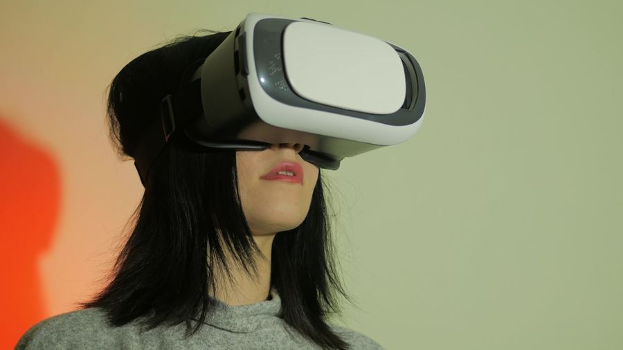 Woman using virtual reality headset against wall