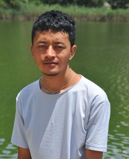 Portrait of young man standing against lake