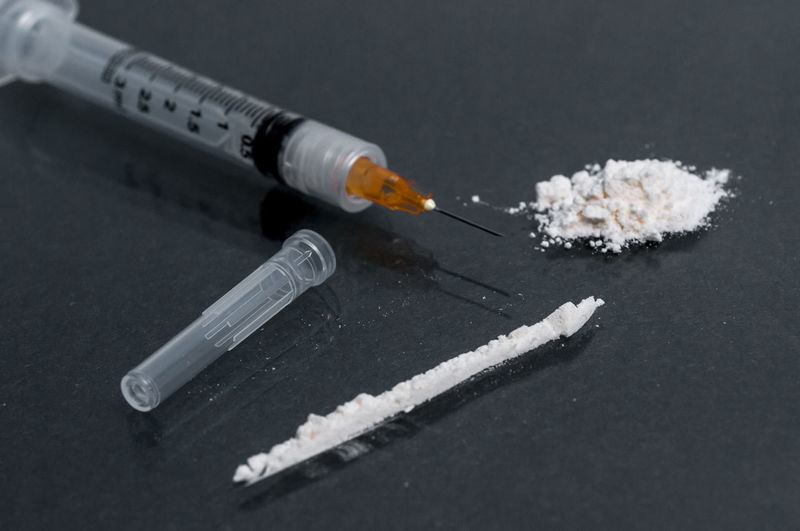 Close-up of syringe with heroin on black table