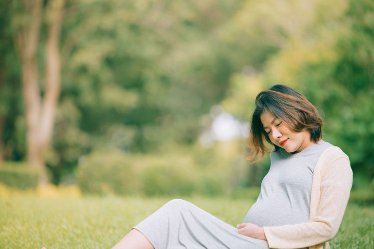 Pregnant woman sitting on grass at park