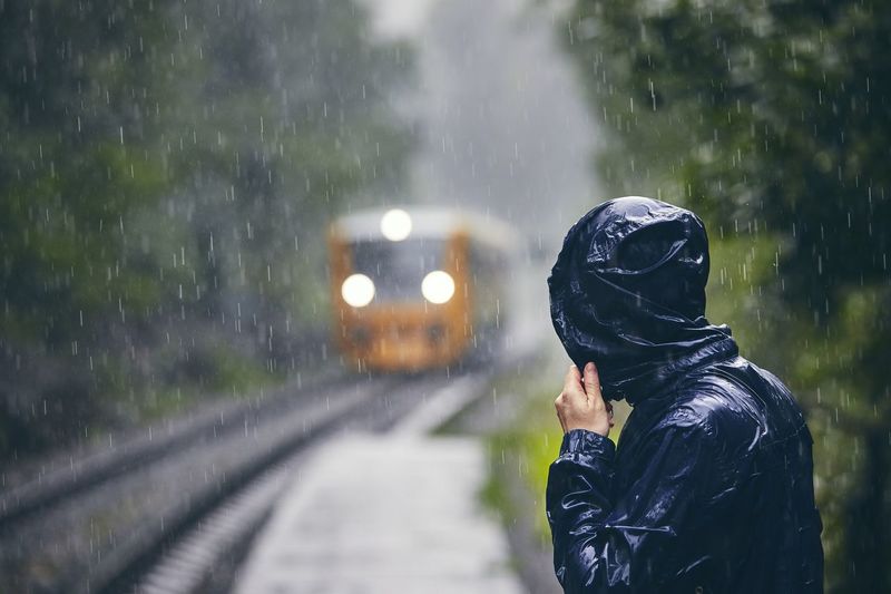 Man standing on wet train during rainy season