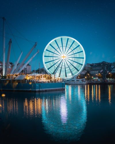 Reflection of illuminated ferris wheel in lake at night