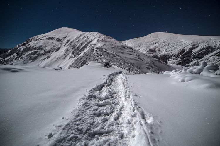 Scenic view of snowcapped mountains against sky at night