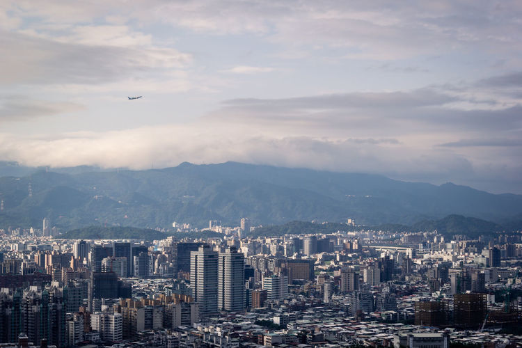 Cityscape of taipei with mountain background and plane in the sky