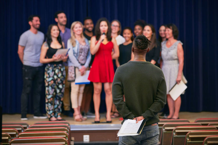 Musical conductor listening to choir on stage in language school