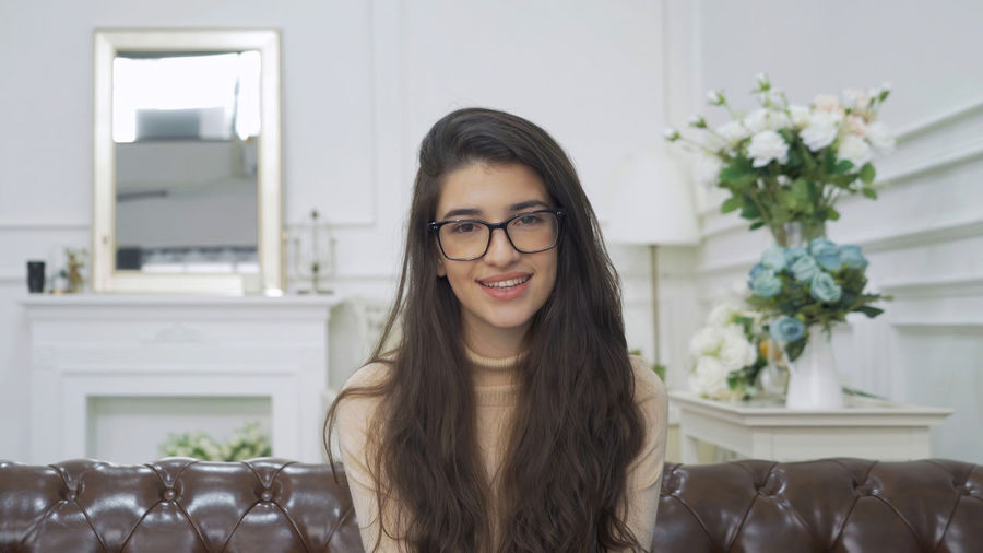 Portrait of smiling young woman sitting at home