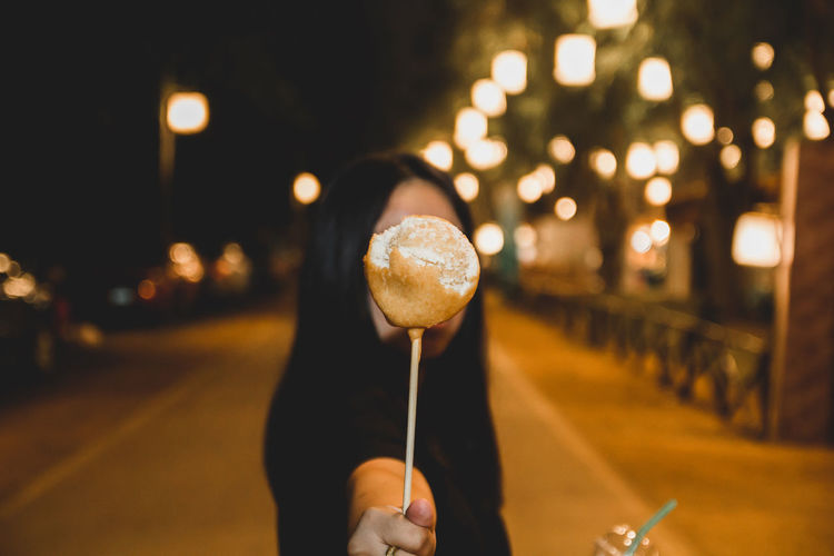 Woman holding candy in illuminated city