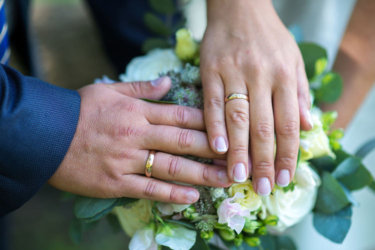 Cropped hands of couple on bouquet