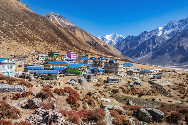 Panoramic view of buildings and mountains against blue sky