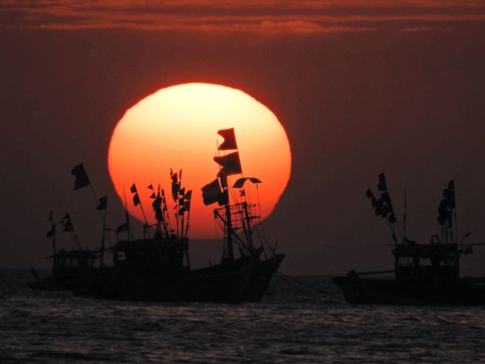 Silhouette fishing boats on sea against sky during sunset