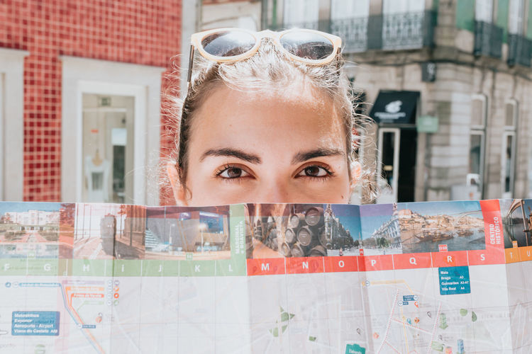Portrait of woman holding map in front of face
