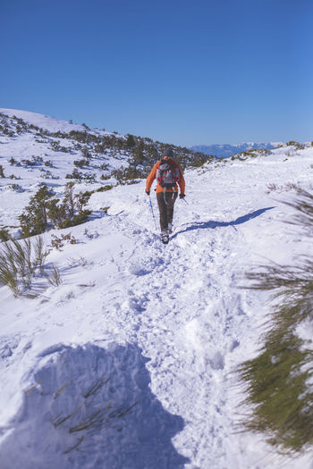 Full length of mature man skiing on snowcapped mountain against sky