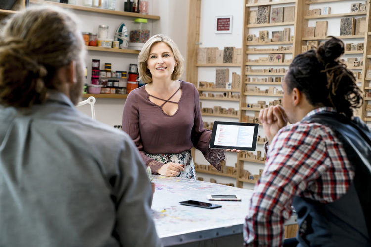 Businesswoman showing data on tablet computer to male colleagues