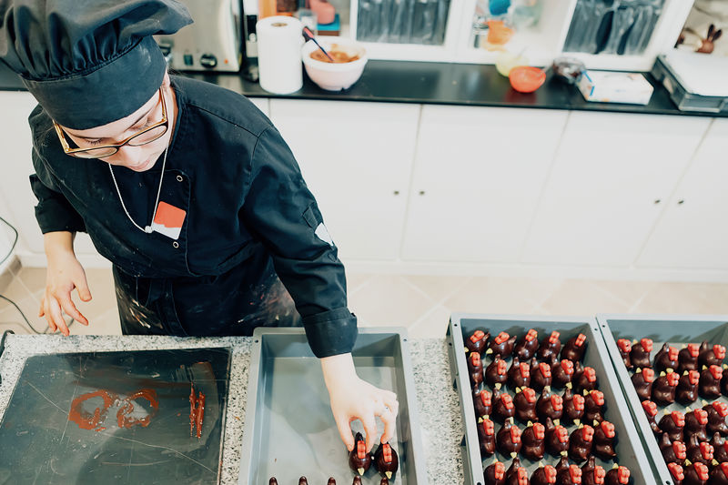 High angle view of female chocolatier in chef uniform working on pastry in the kitchen