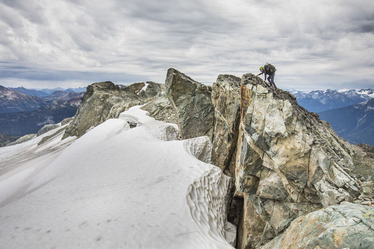Climber approaches summit of a rocky mountain peak.