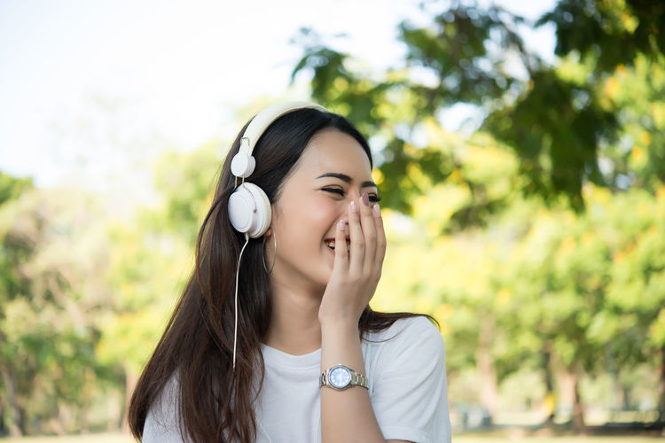 Smiling young woman listening music through headphones