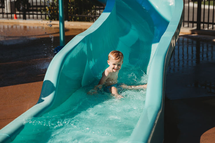 Happy young boy at bottom of water slide