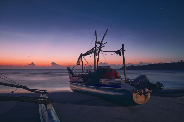 Seascape at colorful dawn. fishing boat on sand beach near tangalle in sri lanka