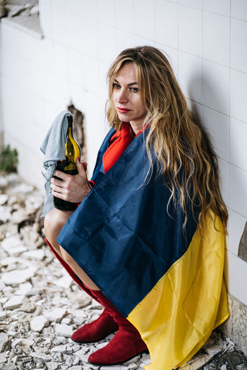 Woman holding ukrainian flag against wall